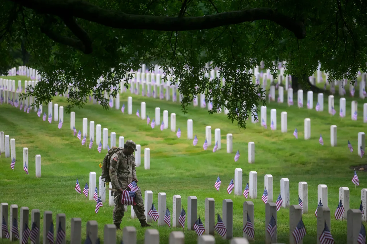 Members of the 3d U.S. Infantry Regiment place a U.S. flag at each headstone during the Annual Flags-In Ceremony at Arlington National Cemetery in preparation for Memorial Day, Thursday, May 21, 2026, in Arlington, Va.
