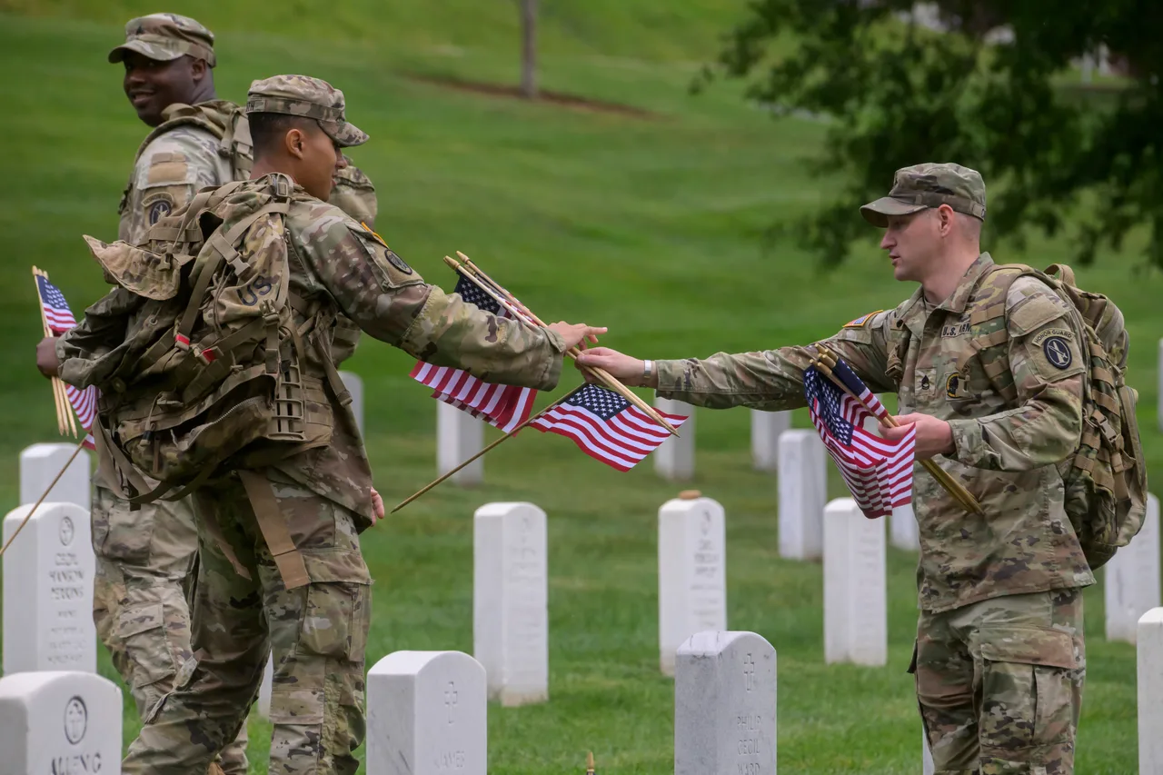 Members of the 3d U.S. Infantry Regiment place U.S. flags at each headstone during the Annual Flags-In Ceremony at Arlington National Cemetery in preparation for Memorial Day, Thursday, May 21, 2026, in Arlington, Va