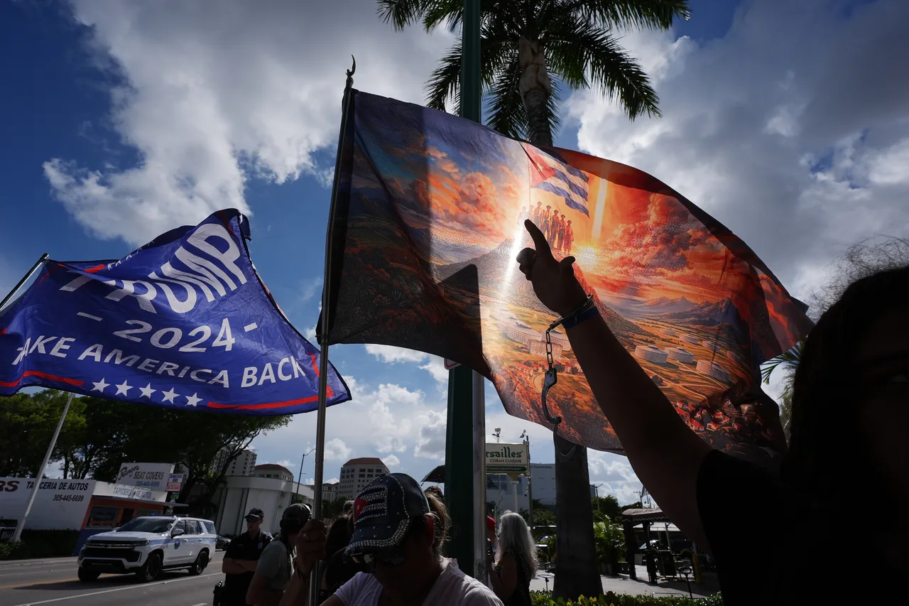 Jose Miguel Hernandez, 14, right, wears handcuffs to represent freedom for political prisoners and a call to put former Cuban President Raul Castro in jail, while his mother Catalina Vasquez waves a flag depicting Cuban political prisoners atop a mountain overlooking prisons below, hours after federal prosecutors announced charges against Castro in the 1996 downing of civilian planes operated by Miami-based exiles, Wednesday, May 20, 2026, in Miami.