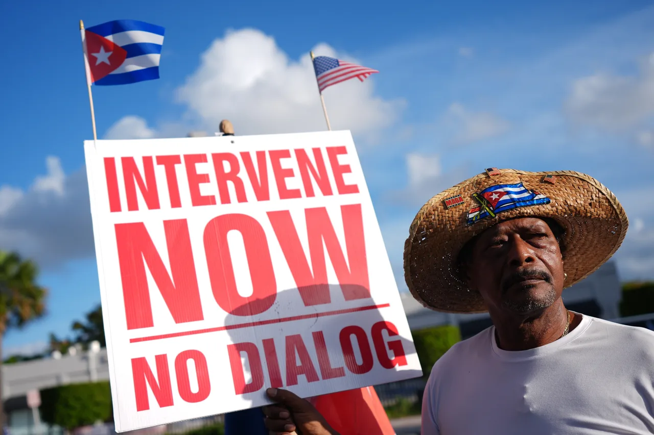 Santiago Ferran holds a sign calling for American intervention in Cuba, as a small group of Cubans turned out to wave flags and hold signs hours after federal prosecutors announced charges against former Cuban President Raul Castro in the 1996 downing of civilian planes operated by Miami-based exiles, Wednesday, May 20, 2026, in Miami.