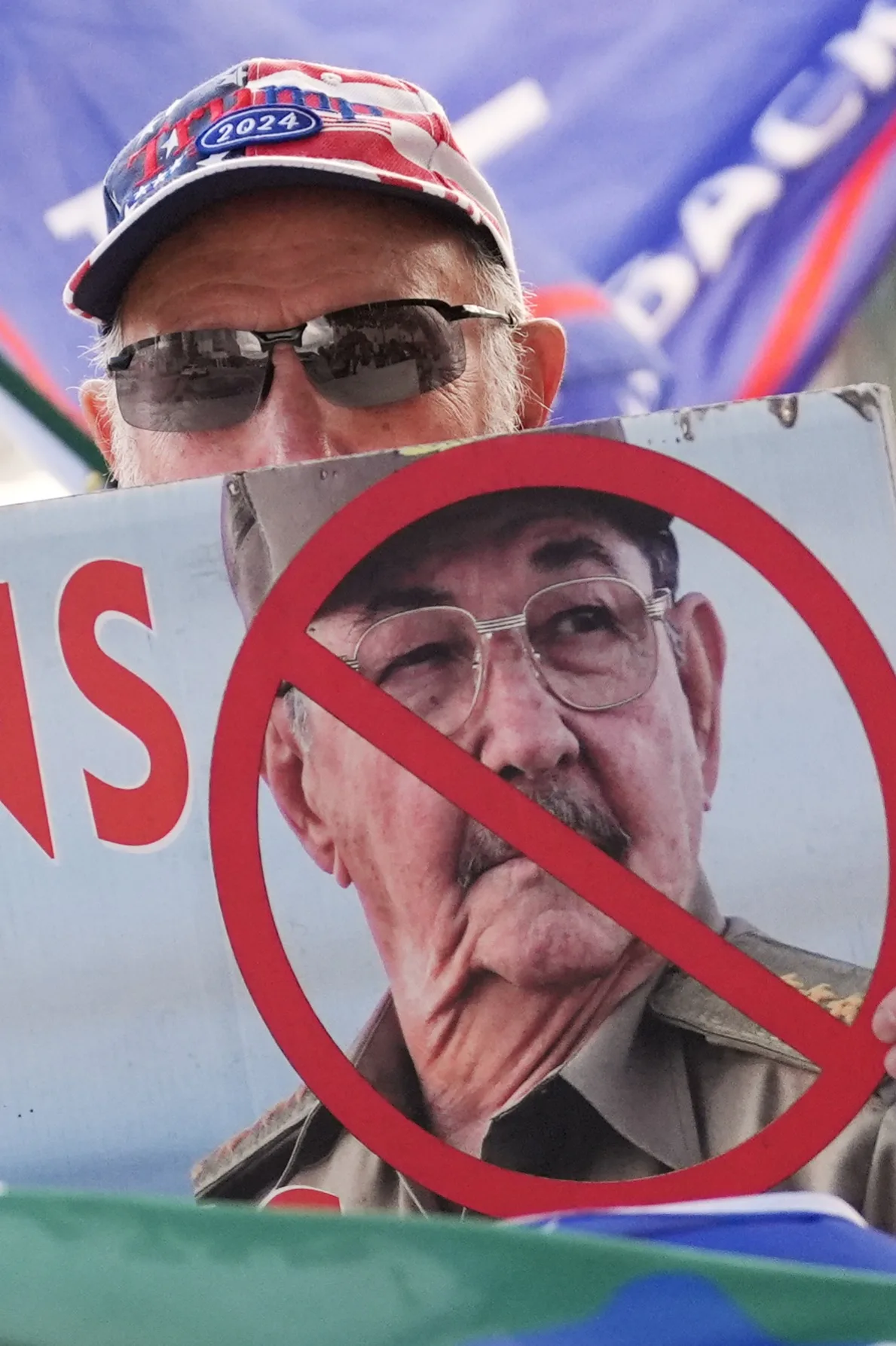 Agustin Acosta holds a placard protesting former Cuban President Raul Castro as a handful of Cubans turned out to wave flags and hold signs hours after federal prosecutors announced charges against Castro in the 1996 downing of civilian planes operated by Miami-based exiles, Wednesday, May 20, 2026, in Miami.