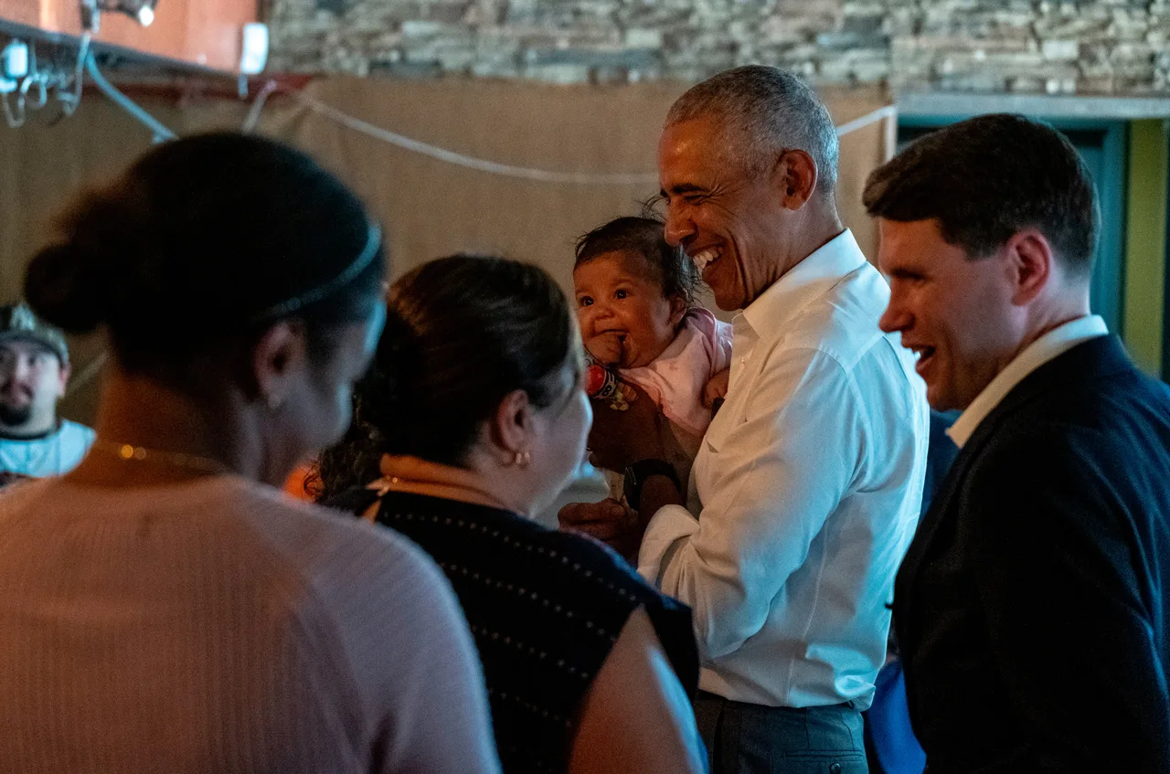Obama holds child while greeting families on campaign trail