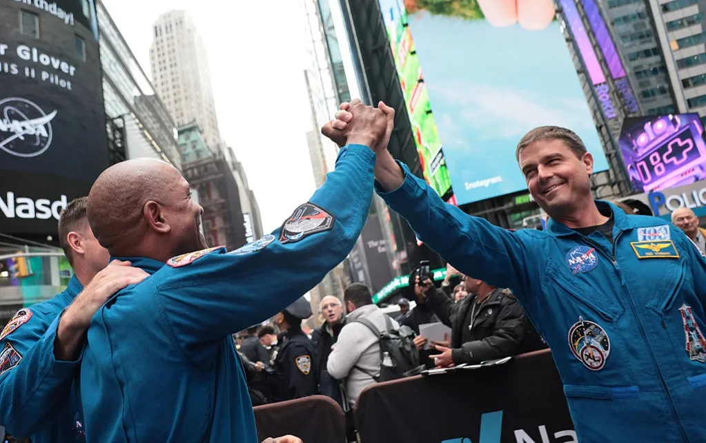 Artemis II Commander Reid Wiseman and Pilot Victor Glover clasp hands outside Nasdaq Marketside